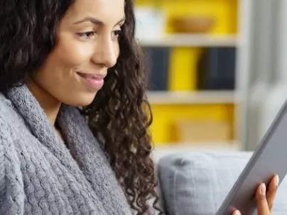 Smiling woman looking at a tablet on a couch