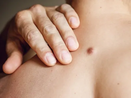 Woman's collarbone with a mole under her hand