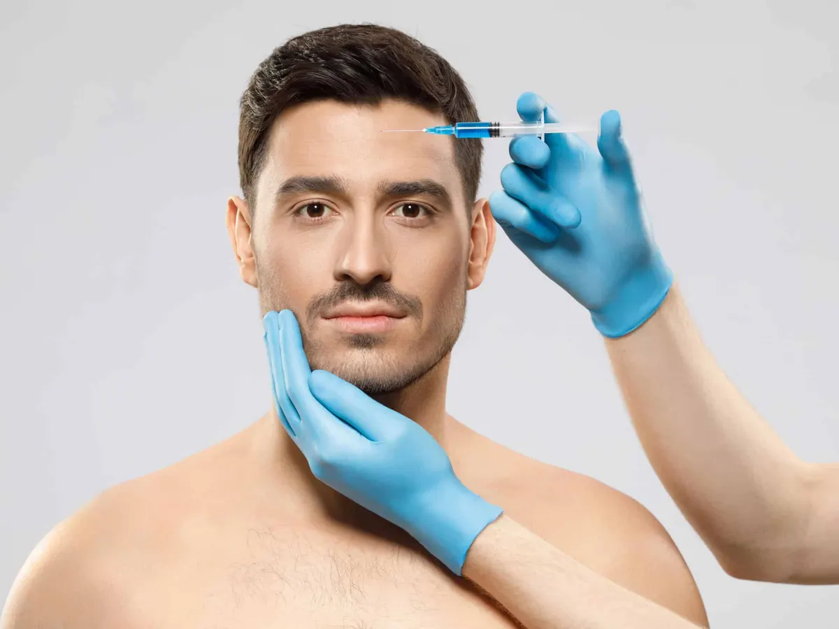 Man receiving an injection at his forehead from a gloved hand