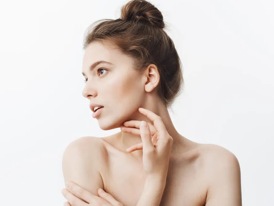 Woman with her hair in a bun and her hand at her neck