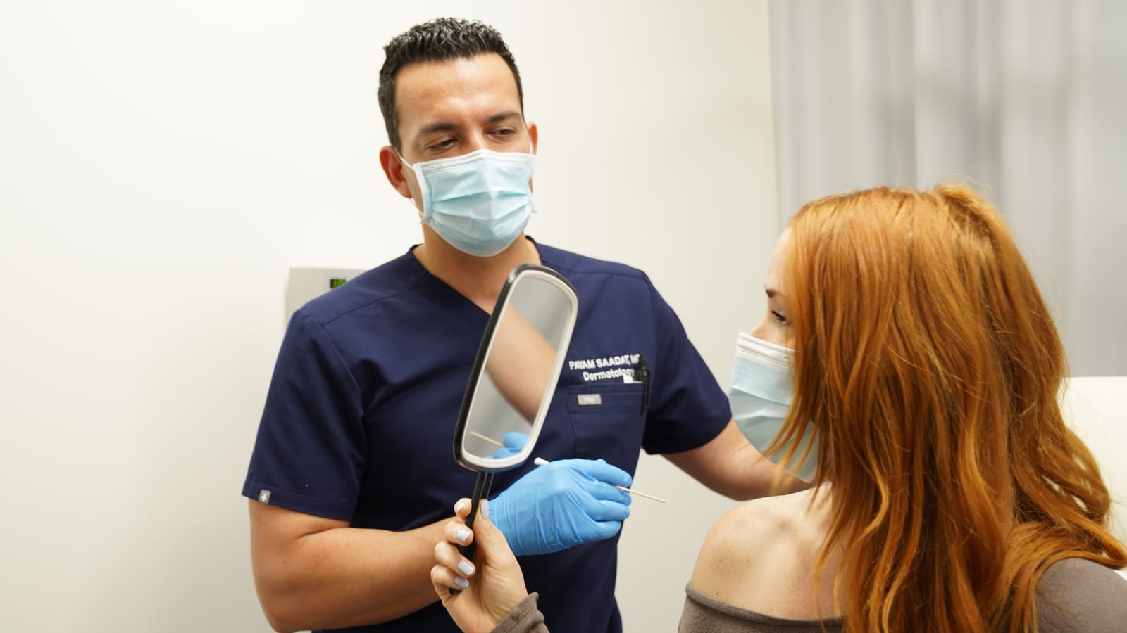Payam Saadat, MD, holding a hand mirror for a patient during a consultation
