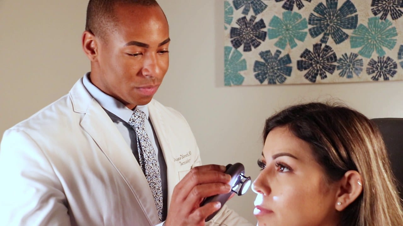 A dermatologist examining a patient's skin with a dermatoscope