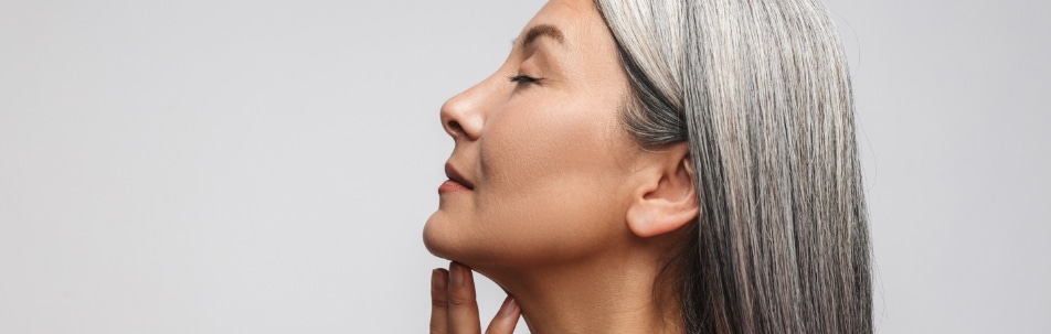 Side view of a woman with gray hair, eyes closed, fingers resting under her chin