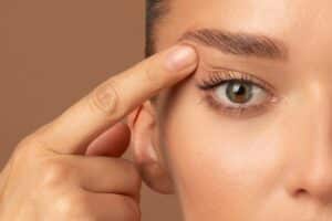 Close up of woman's eye touching her eyelid wanting eyelid surgery in Los Angeles, CA