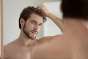 Man looking in the mirror at hair after Growth Factor Hair Restoration in Los Angeles, CA