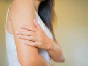 Woman touching her arm due to possible psoriasis or eczema in Los Angeles
